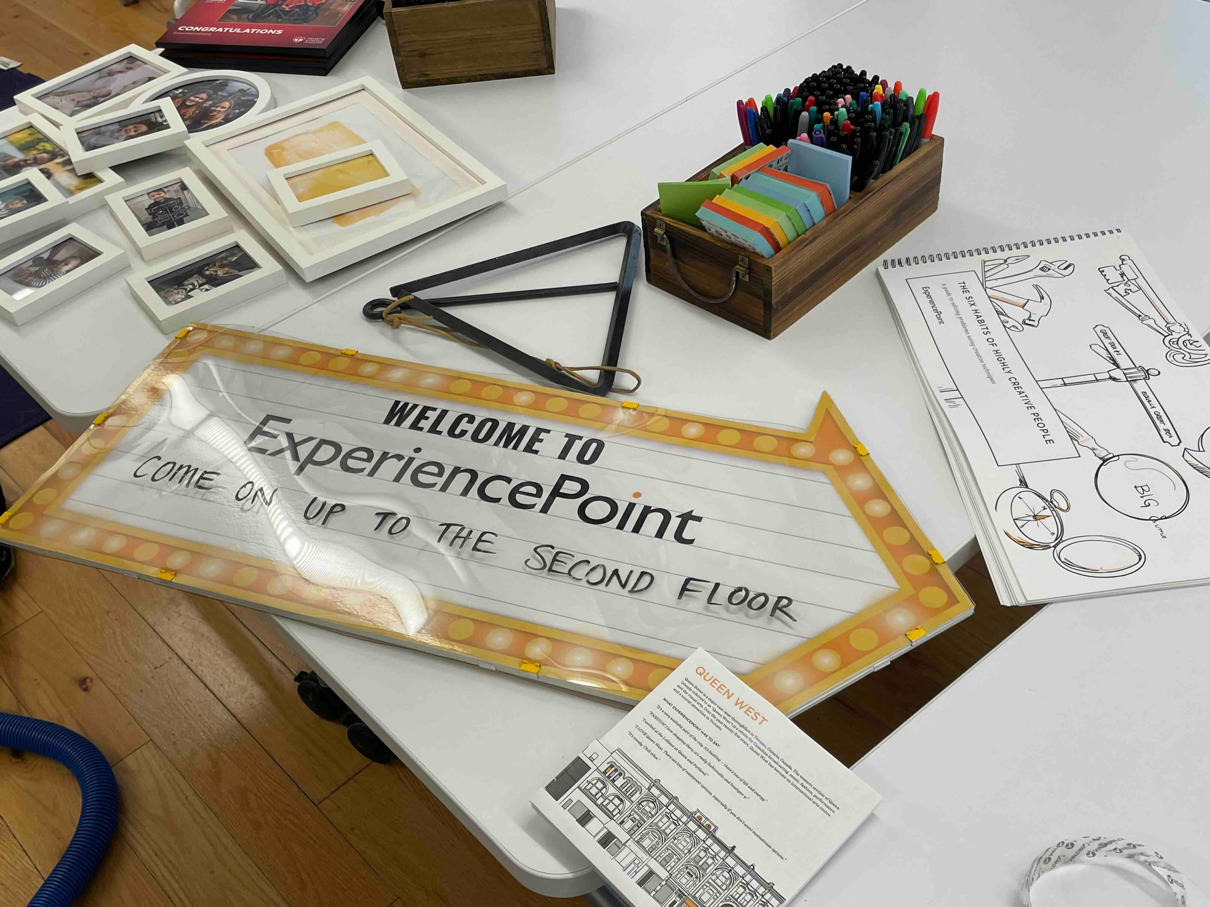 An office sign that says "Welcome to ExperiencePoint!" lies astray on a table as it gets unpacked in a new office space.